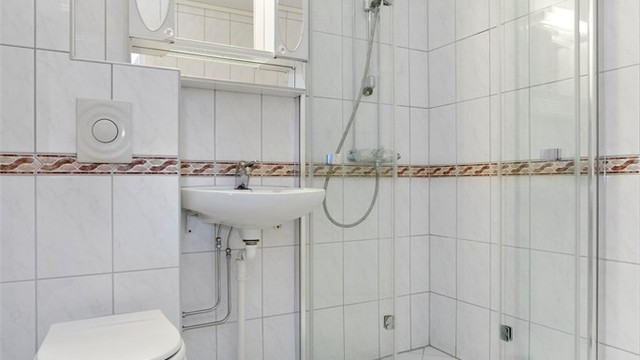 Flislagt bad med gulvvarme, vegghengt toalett og opplegg for vaskemaskin.