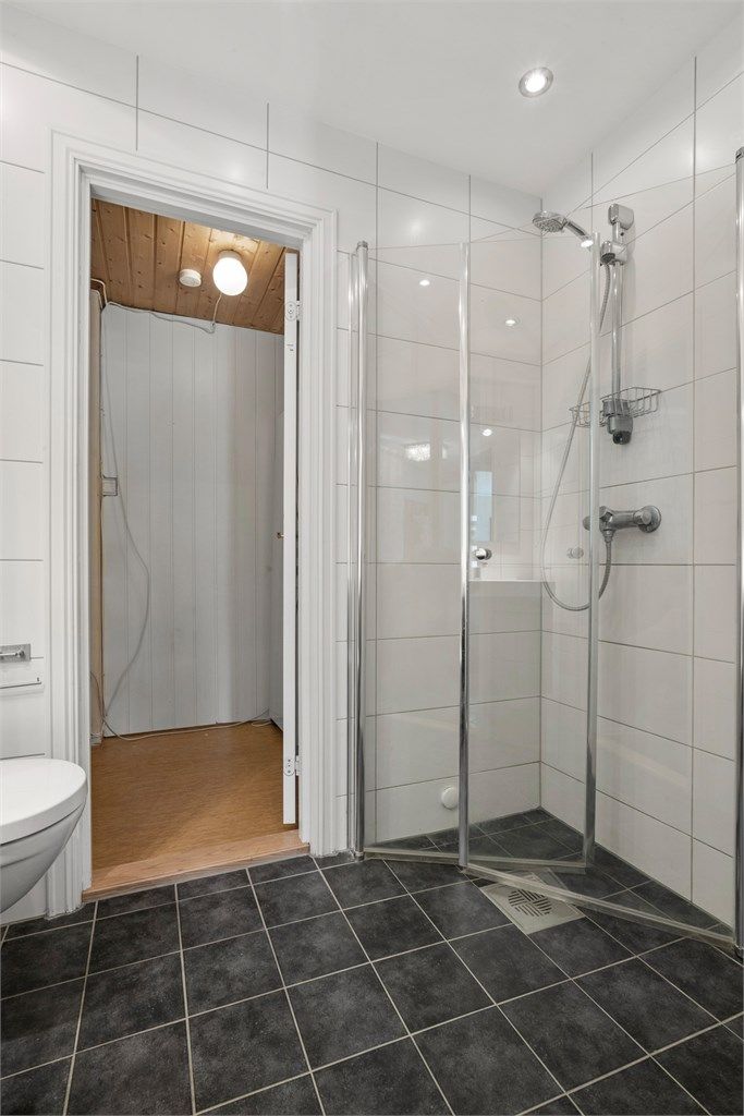 Dusjhjørne med innfellbare glassdører og downlights i taket.