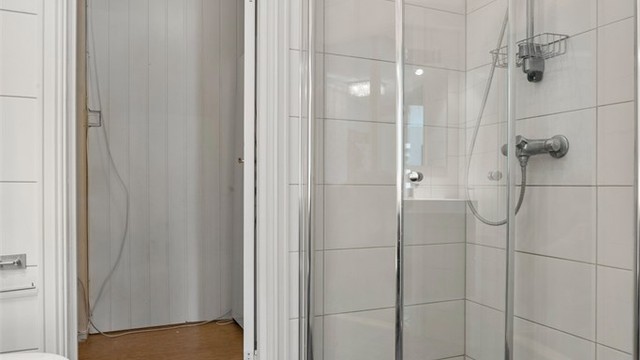 Dusjhjørne med innfellbare glassdører og downlights i taket.