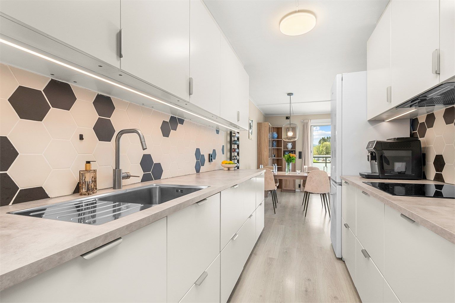 Kjøkkenet ligger naturlig tilbaketrukket fra stuen og er innredet med lyse slette flater og benkeplate av laminat. Her har man rikelig med skap- og benkeplass å boltre seg på! 