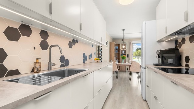 Kjøkkenet ligger naturlig tilbaketrukket fra stuen og er innredet med lyse slette flater og benkeplate av laminat. Her har man rikelig med skap- og benkeplass å boltre seg på!
