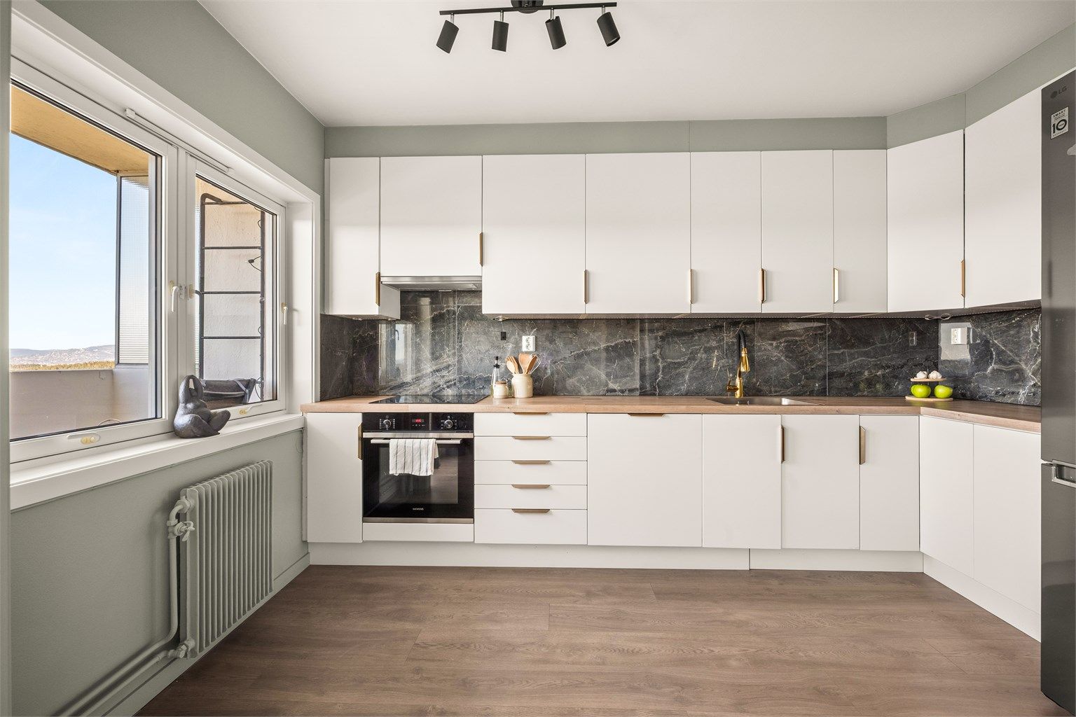 Stilrent kjøkken med glatte fronter, laminert benkeplate og fliser mellom benk og overskap.