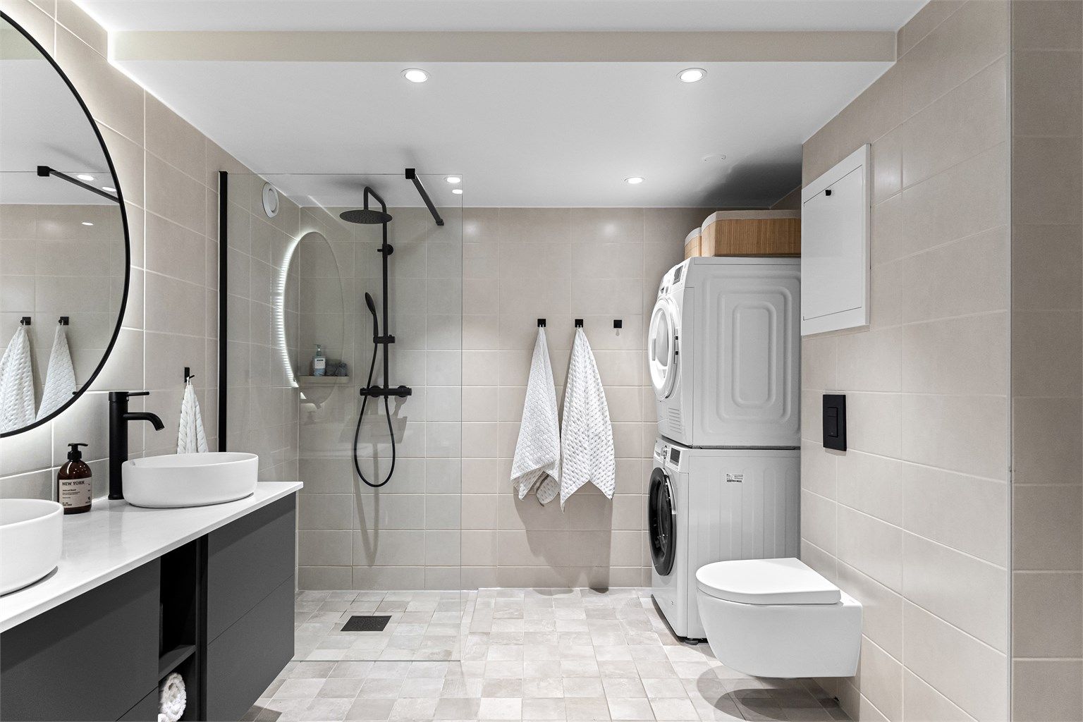 Badet har et tidsriktig og moderne uttrykk, og er innredet med vegghengt toalett, servantskap med dobbel servant, speil med belysning og dusjhjørne med glassdør.