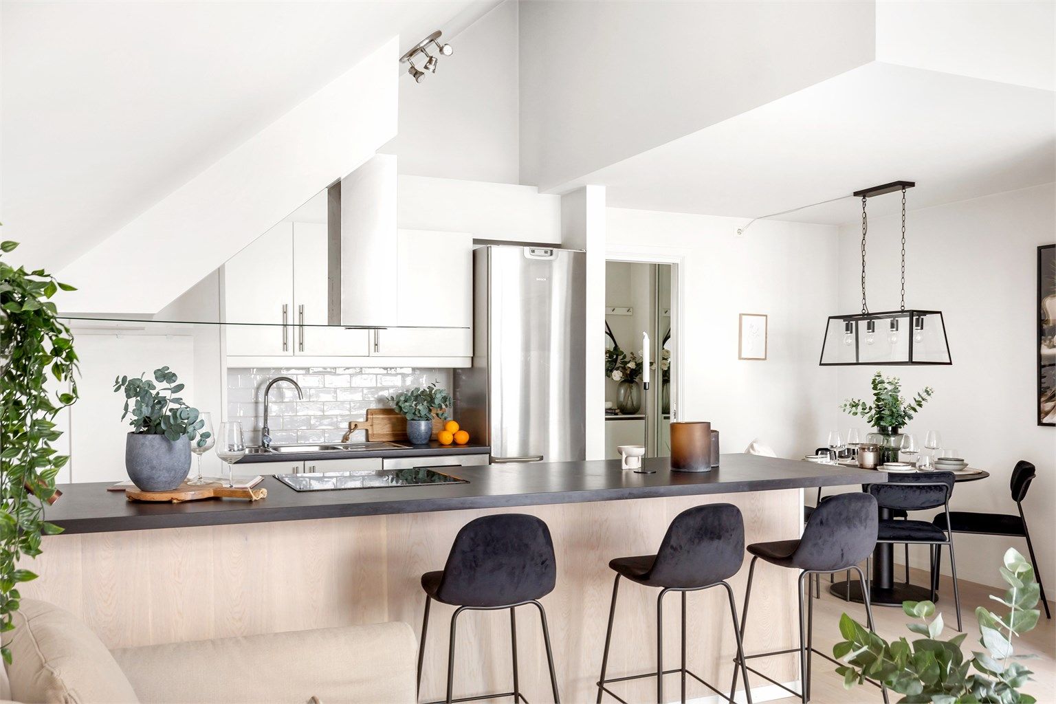 Stilrent kjøkken med barløsning, integrerte hvitevarer og plass til hyggelige måltider rundt spisebordet.