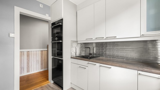 Stilrent kjøkken med glatte fronter og laminert benkeplate.
