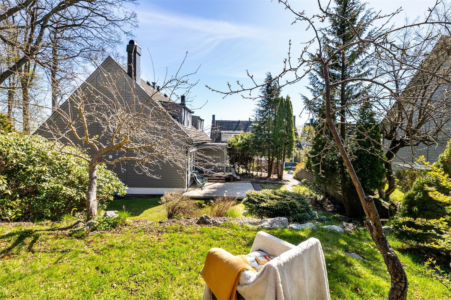 Tomannsboligen i Anna Hagmans gate 3K er tilbaketrukken inntil skogholt og omgis av en romslig, veletablert hage med masse boltreplass for familien. Fotograf; Børge Oppegård.