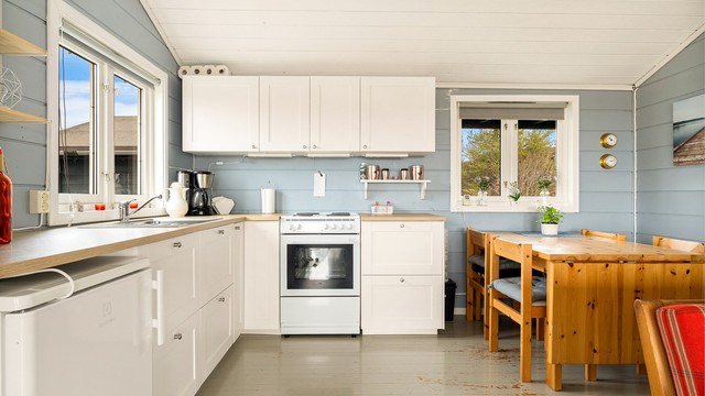 Åpen kjøkkenløsning med Ikea innredning fra ukjent årstall med profilerte fronter og benkeplate med laminat overflate