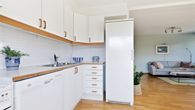 Kjøkkenet er i direkte kontakt med spiseplassen og har fin benkeplass. Kjøkkenet er originalkjøkkenet med fin rustfri oppvaskkum og avtrekk ut over komfyrplassen. Lys under overskap for arbeidslys på benk.