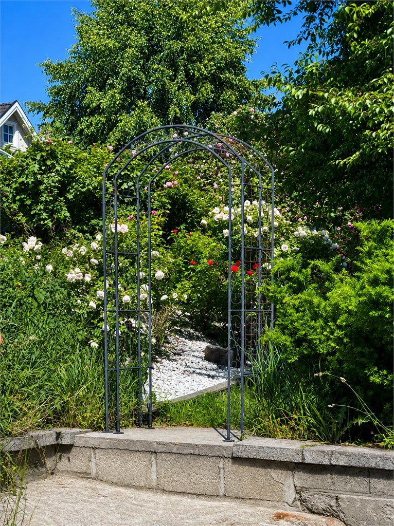 Roseportalen markerer inngangen til et stemningsfullt hageanlegg med frodig beplantning og flotte oppholdsarealer. 