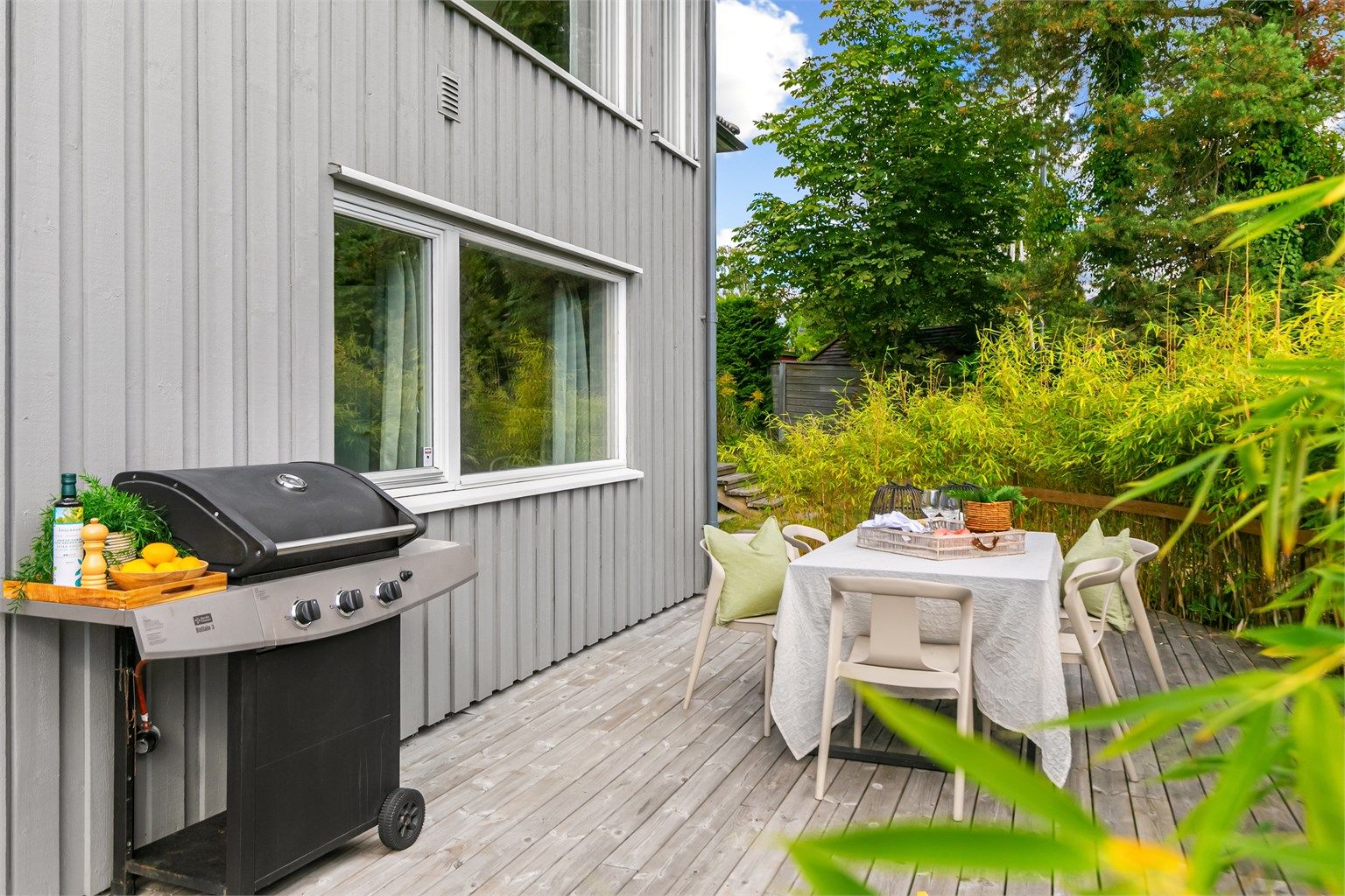 Platting med spisebord og god plass til grill ved husveggen.