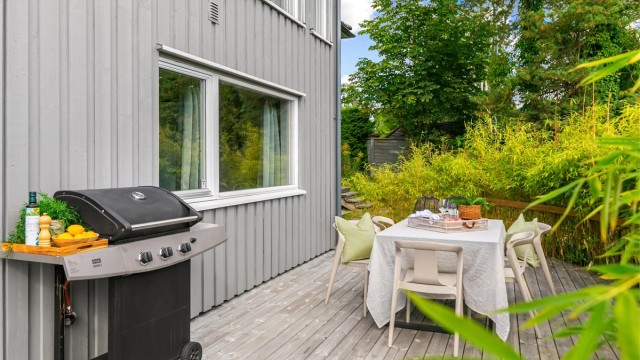 Platting med spisebord og god plass til grill ved husveggen.