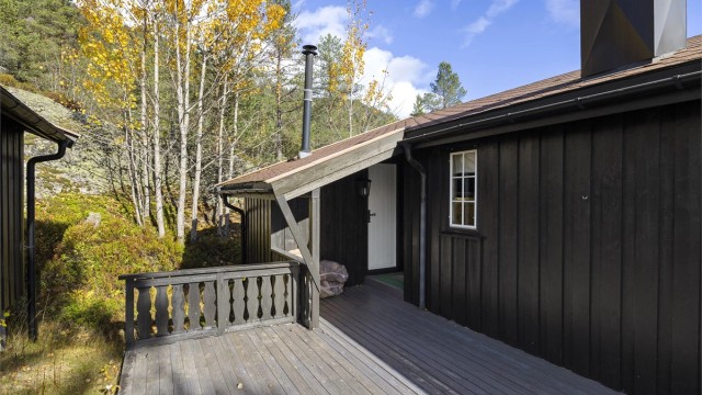 Overbygd inngangsparti med treterrasse som binder hytta og annekset sammen.