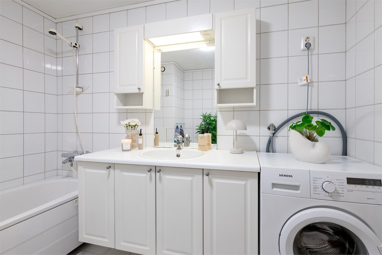 Hvit baderomsinnredning med god skapplass. Nedfelt vask og overskap med lys. Plass til vaskemaskin på badet. Varmekabler i gulv. 