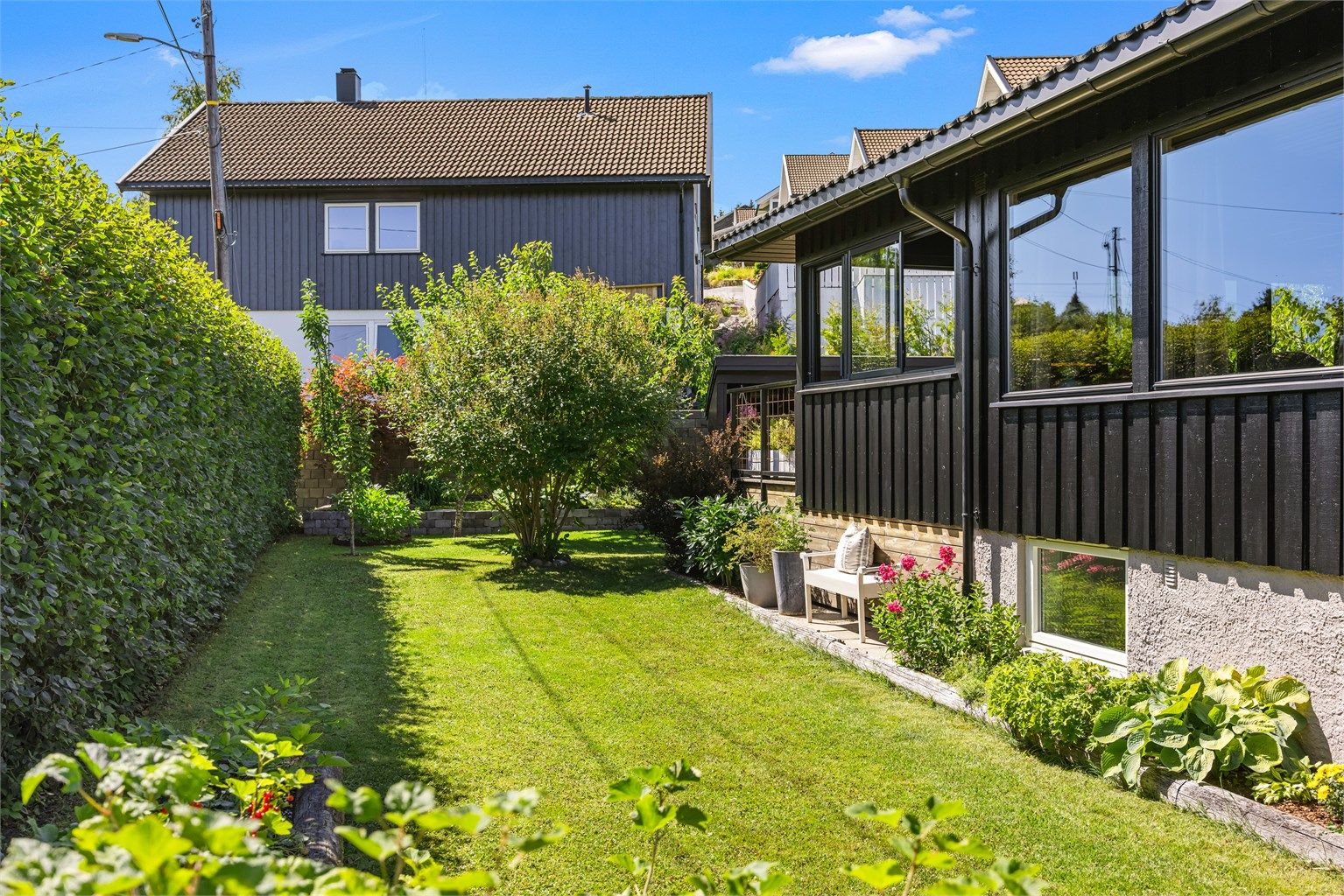 Den velholdte hagen er pent opparbeidet med plen og beplantning som skaper et grønt og innbydende utemiljø.