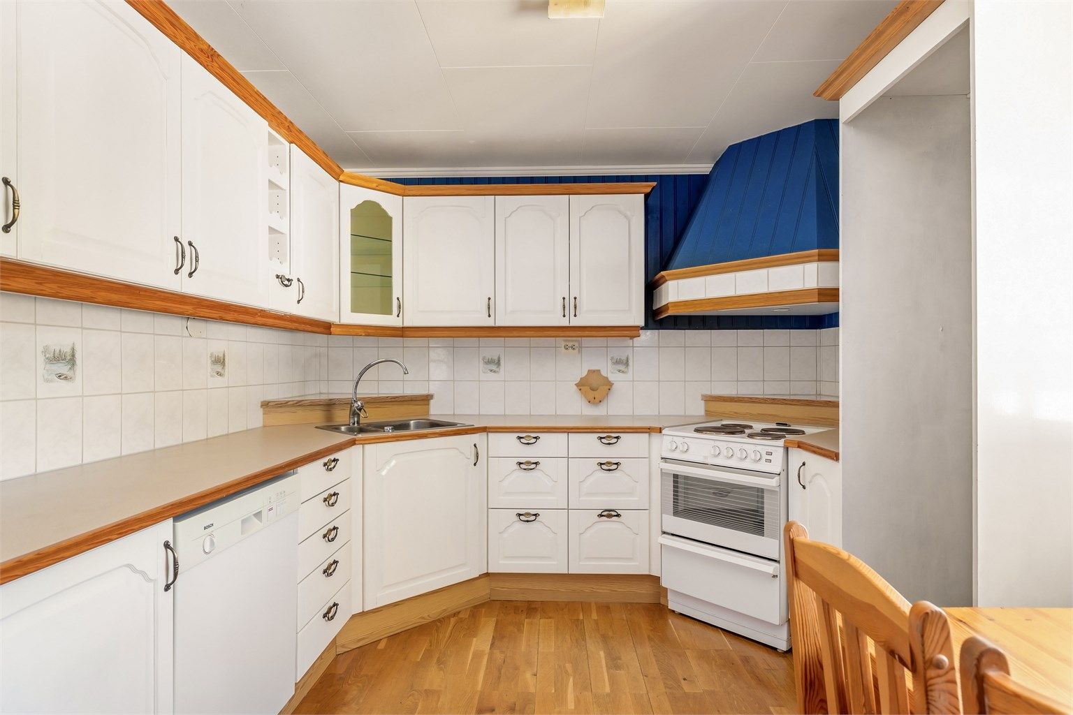 Kjøkken med spiseplass og innredning med malte heltre fronter.