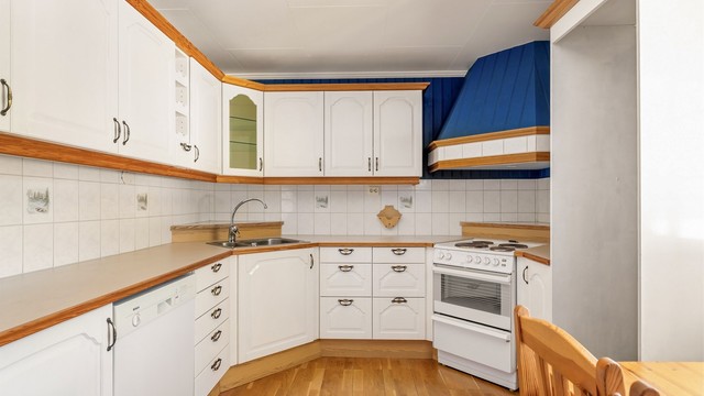 Kjøkken med spiseplass og innredning med malte heltre fronter.