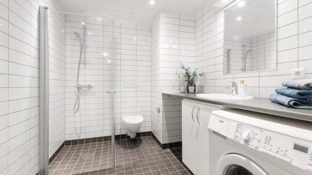 Flislagt baderom med gulvvarme, downlights og opplegg for vaskemaskin.