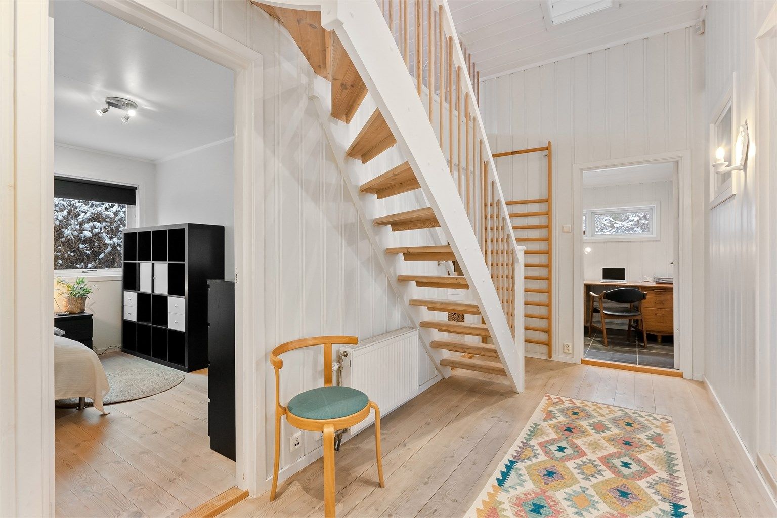 Gangen har furugulv og malt panel, og forbinder soverommene i denne fløyen.