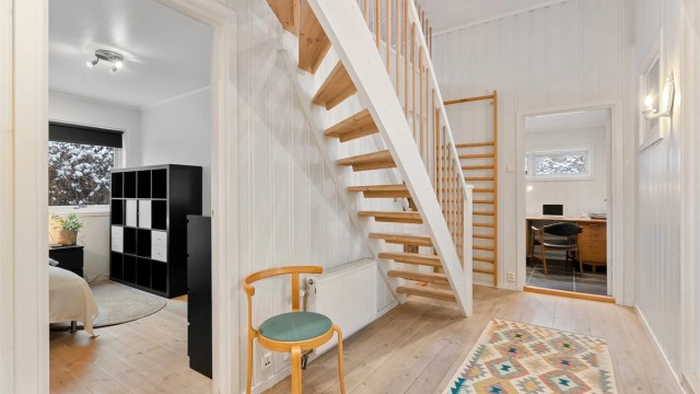 Gangen har furugulv og malt panel, og forbinder soverommene i denne fløyen.