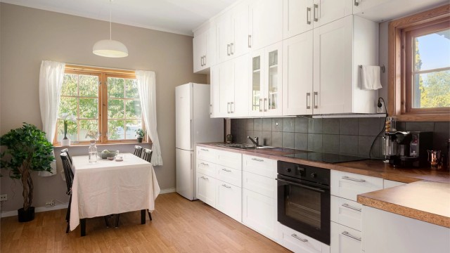 Stort spisekjøkken med profilerte fronter, laminert benkeplate og plass til spisebord ved vinduet.