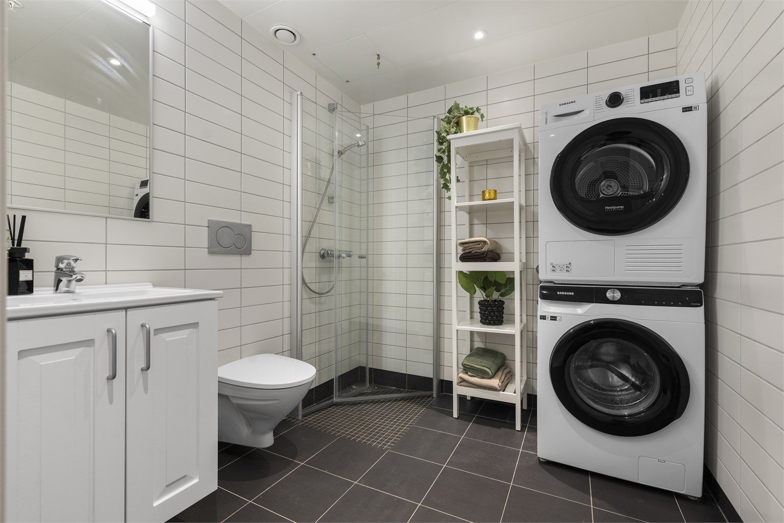 Flislagt og moderne baderom med vegghengt toalett og dusjhjørne.