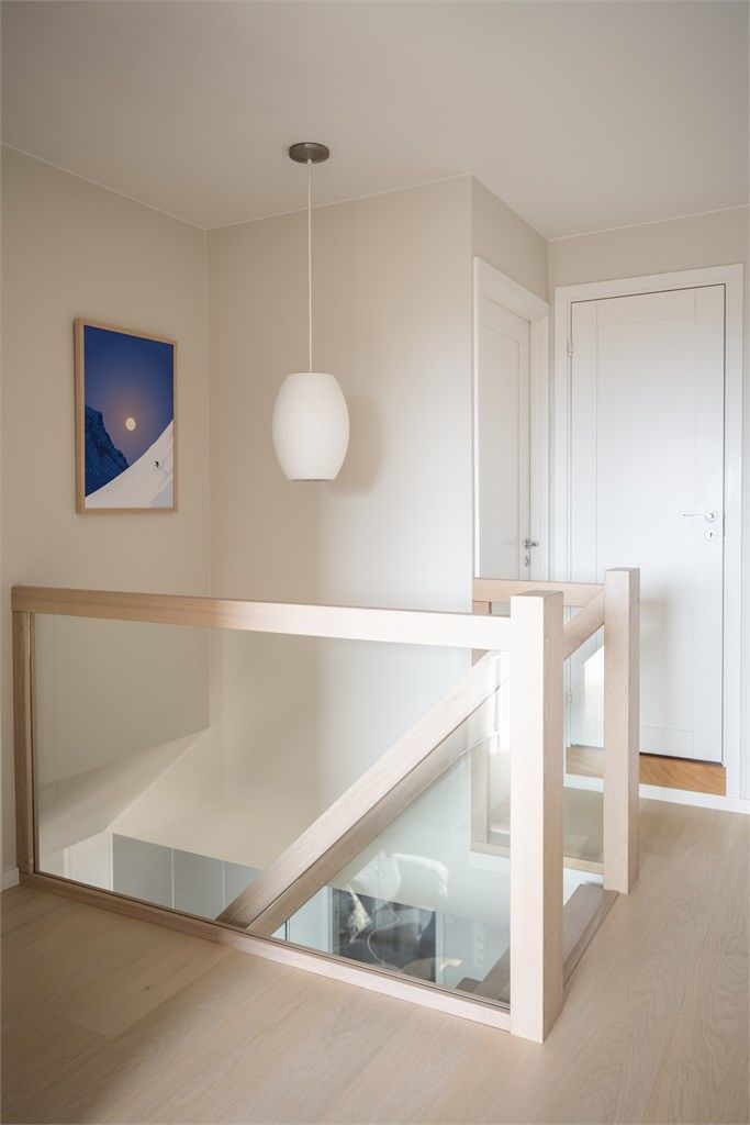 Ankomst til øvre plan. Rekkverket i glass og tre viderefører det lette uttrykket fra etasjen under.