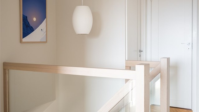 Ankomst til øvre plan. Rekkverket i glass og tre viderefører det lette uttrykket fra etasjen under.