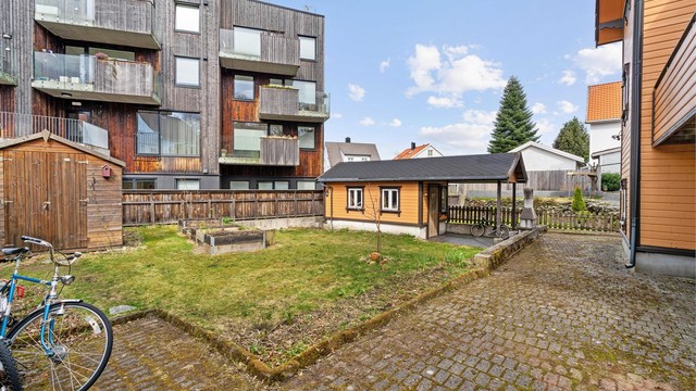 Felles uteområde med plen og belegningsstein.