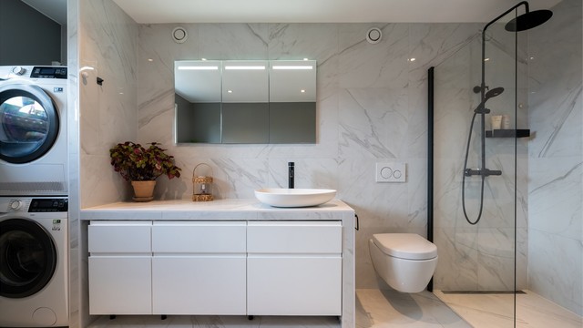 Badet er innredet med servantskap med ovenpåliggende vask, speil med belysning over servant og vegghengt toalett.