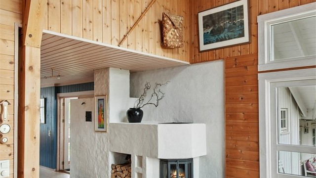 Den plassbygde peisen har to brennkamre. Brennkammeret som vender mot spisestuen bidrar også til oppvarming av det vannbårne systemet når det fyres med ved.