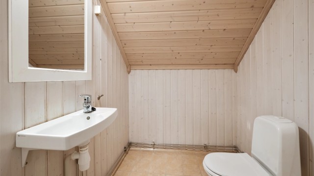 Separat toalettrom i andre etasje med flislagt gulv og panel på veggene.