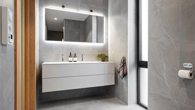 Badet er delikat utformet og av god størrelse og har lekre detaljer, flislagte vegger og gulv, servant med dobbel kran, badekar, dusjhjørne og vegghengt toalett.