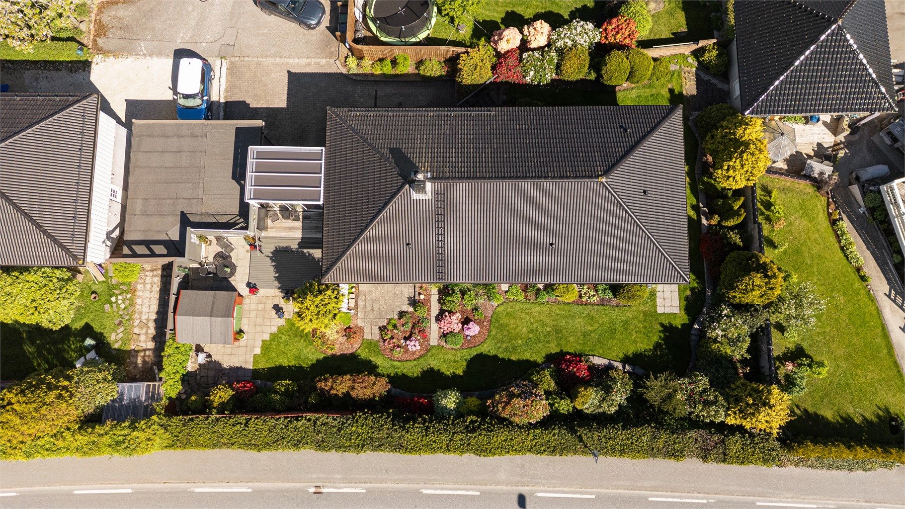 Tomten er opparbeidet med belegningsstein, plen og beplantning.
