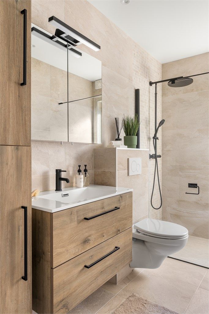 Baderomsinnredning med sorte detaljer, speilskap og et praktisk høyskap for oppbevaring.