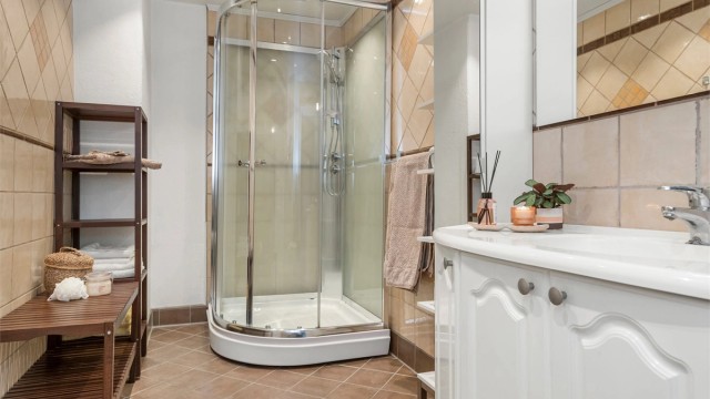 Dusjkabinett med buede glassdører og downlights i himling.