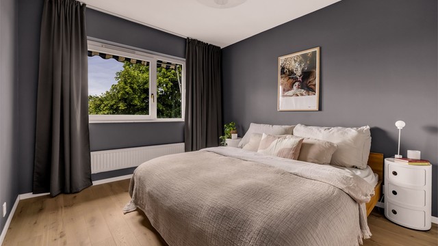 Romslig soverom med god plass til dobbeltseng og nattbord på hver sin side.