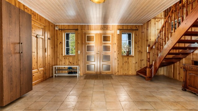 Romslig hall med flislagt gulv, gulvvarme og trapp til loftsetasjen.