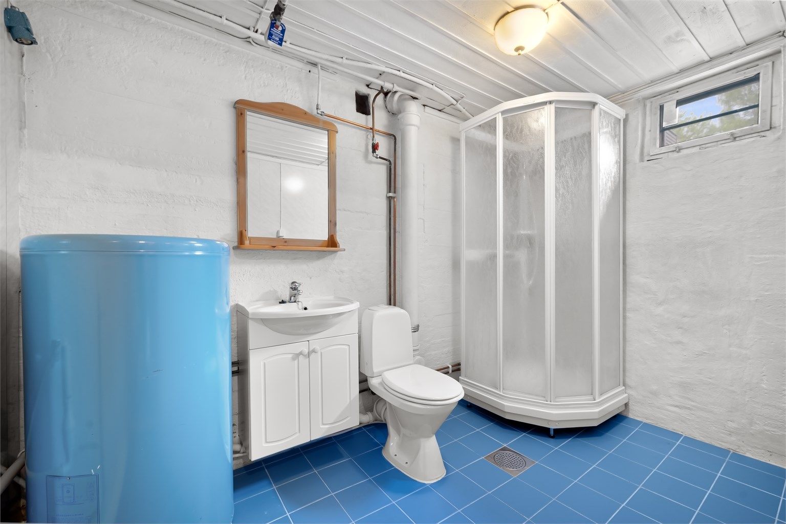 Baderom i kjelleren med dusjkabinett, toalett og opplegg for vaskemaskin. Det må påregnes totalrenovering.