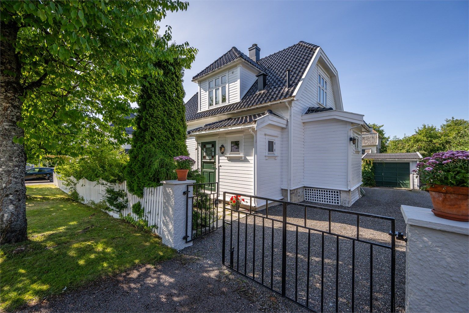 Hagen ligger skjermet mot gaten med hekk, gjerde og port. Innkjørsel og gårdsplass er gruset.
