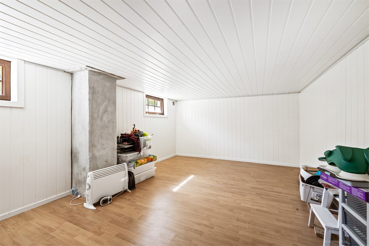 Innredet kjellerstue i kjelleren med laminatgulv og panelplater på veggene. Rommet er ikke byggemeldt.