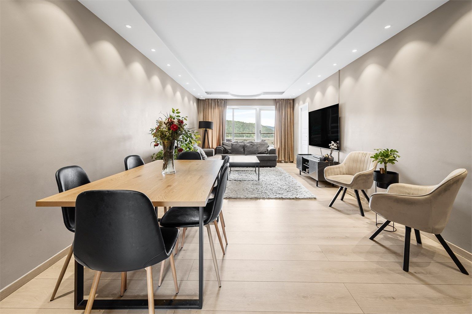 Lys og lun stue med sofaområde, sittegruppe samt spiseplass.