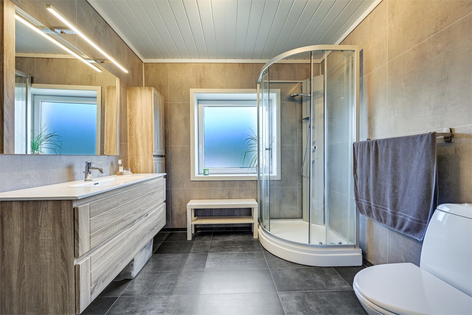 Badet har elektrisk gulvvarme og er innredet med dusjkabinett og en romslig servantinnredning.