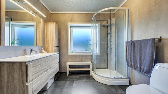 Badet har elektrisk gulvvarme og er innredet med dusjkabinett og en romslig servantinnredning.