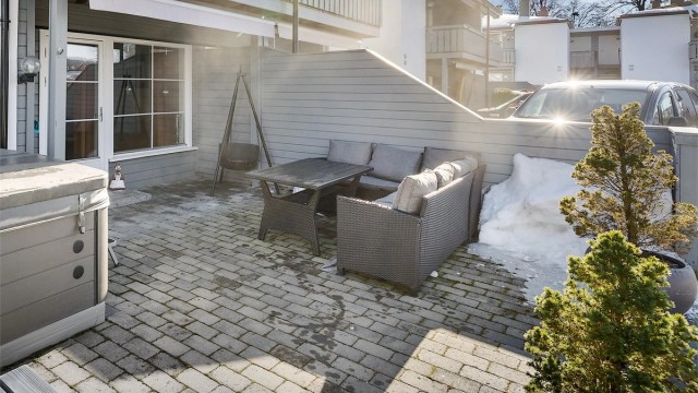 Uteplassen er belagt med lettstelt belegningsstein, og markisen skjermer for solen.