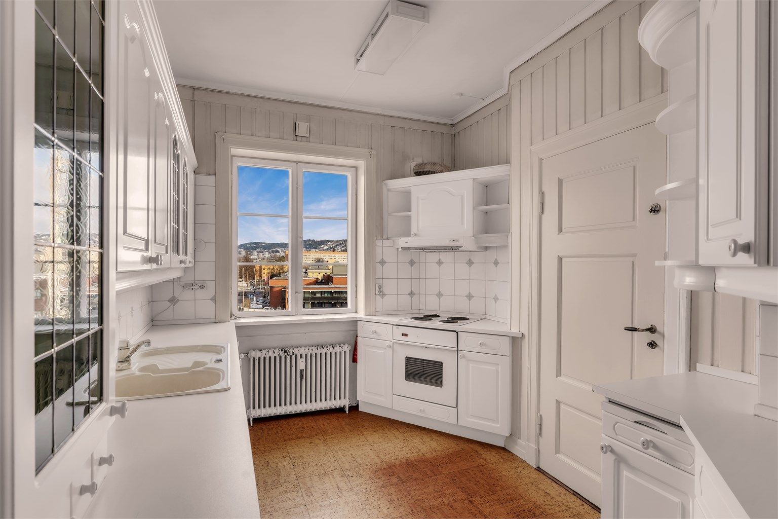 Hyggelig kjøkken med profilerte skapfronter og benkeplater av laminat med nedfelt oppvaskkum i stål. Utgang til bakgård via baktrapp fra kjøkkenet.