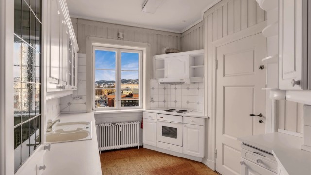 Hyggelig kjøkken med profilerte skapfronter og benkeplater av laminat med nedfelt oppvaskkum i stål. Utgang til bakgård via baktrapp fra kjøkkenet.