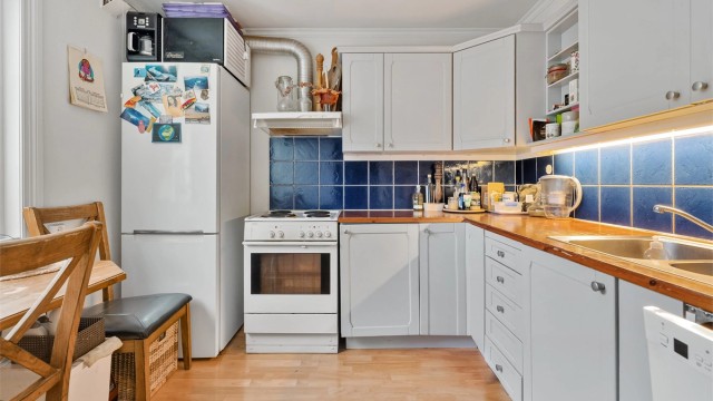 Kjøkkenet i sokkelleiligheten har profilerte fronter, benkeplate i heltre og frittstående hvitevarer.