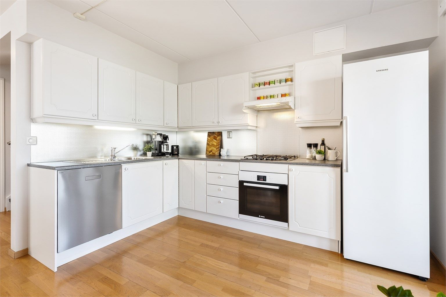 Åpen kjøkkenløsning. Innredning fra byggeår. Profilerte fronter. Benkeplate med laminert overflate. Kjøkkenvask med armatur.