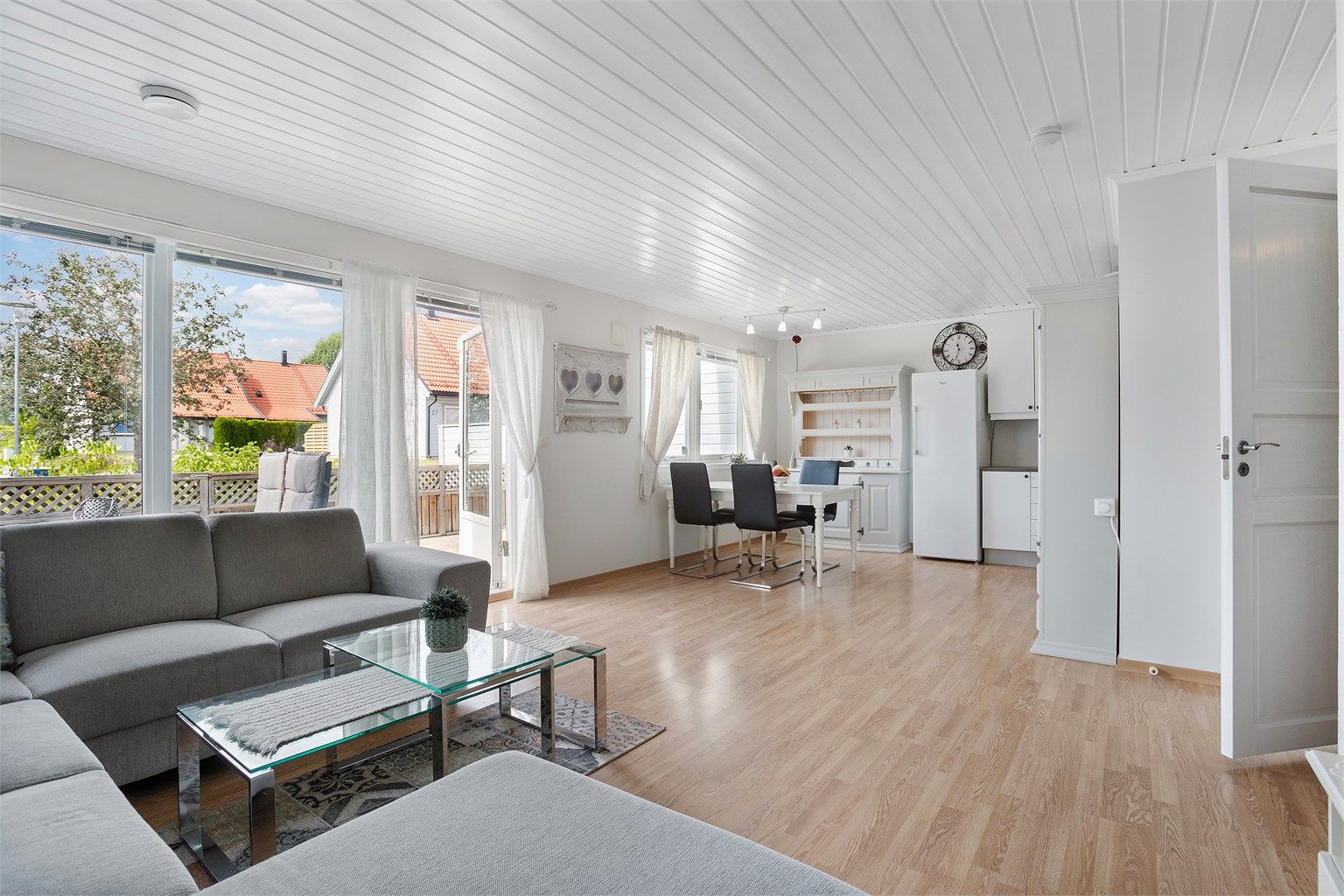 Stue og kjøkken i åpen løsning med laminatgulv og malte, slette vegger.