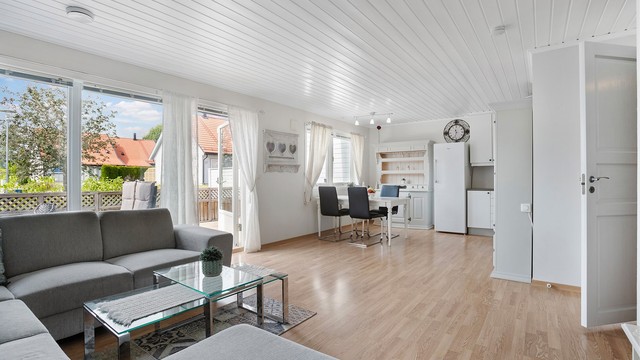 Stue og kjøkken i åpen løsning med laminatgulv og malte, slette vegger.